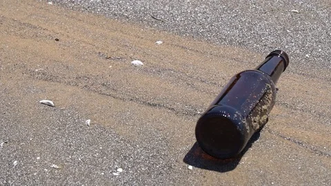 STATIC TIGHT SHOT OF DISCARDED EMPTY BEER BOTTLE ON BEACH Stock Footage 106127770