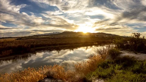 Static time lapse of a golden sunset with the sky reflecting off the river Stock Footage 106736592