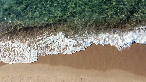 Static top down aerial view: green ocean waves gently crushing on a sandy beach Stock Footage 146193830