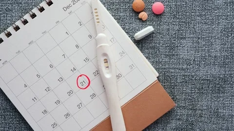 A static top-down view of a calendar with a circled date, a pregnancy test,.. Stock Footage 333030354