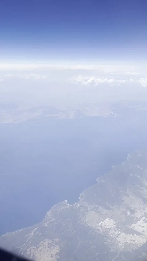 Static vertical shot of an aerial view of land and ocean from a flight window Stock Footage 336517723