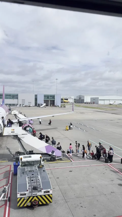 Static vertical shot of distant passengers boarding an airplane on the tarmac Stock Footage 336494495