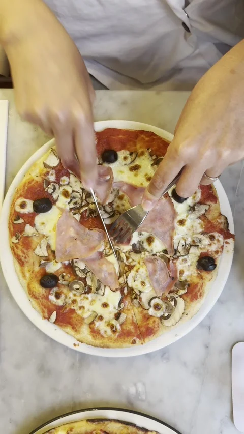 Static vertical shot of female hands cutting pizza in half with knife Video stock 336865785