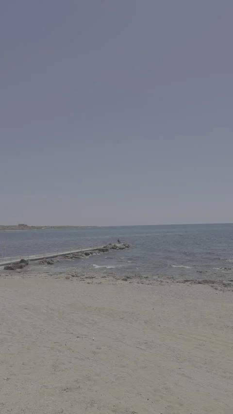 Static vertical shot of flat log footage of sandy beach and stone breakwater Stock Footage 336636995