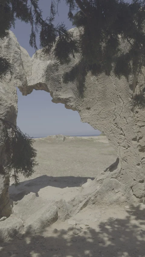 Static vertical shot of flat log footage looking through stone arch to the sea Stock Footage 336637995