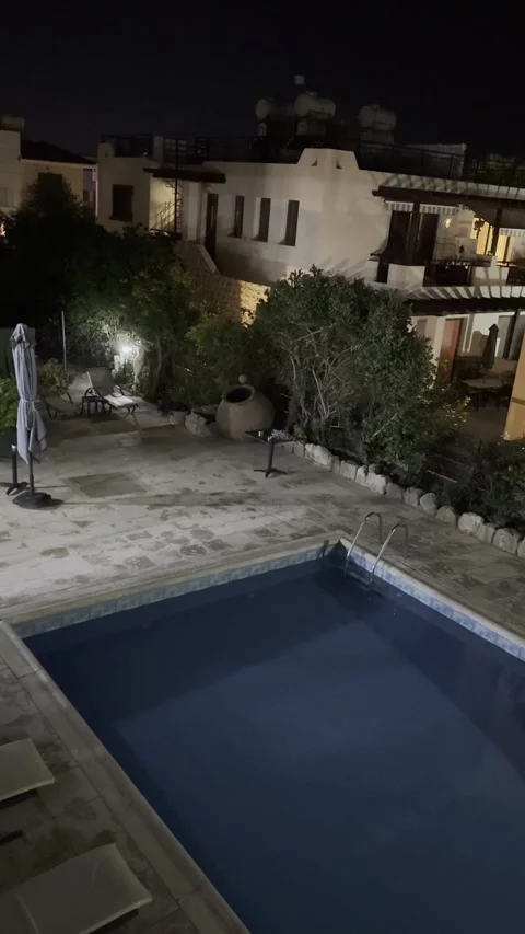 Static vertical shot of a guest house courtyard with a pool at night in cyprus Stock Footage 336517734