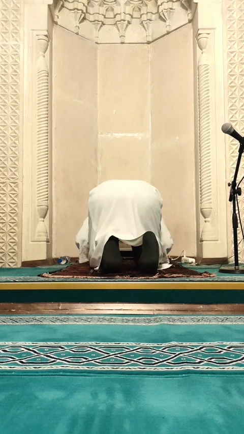 Static vertical shot of an Imam performing Ruku (bowing) in a stone Mihrab. Stockbeeldmateriaal 333605975