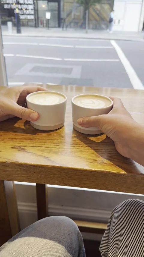 Static vertical shot of two hands holding coffee cups looking out to street Video stock 336680079