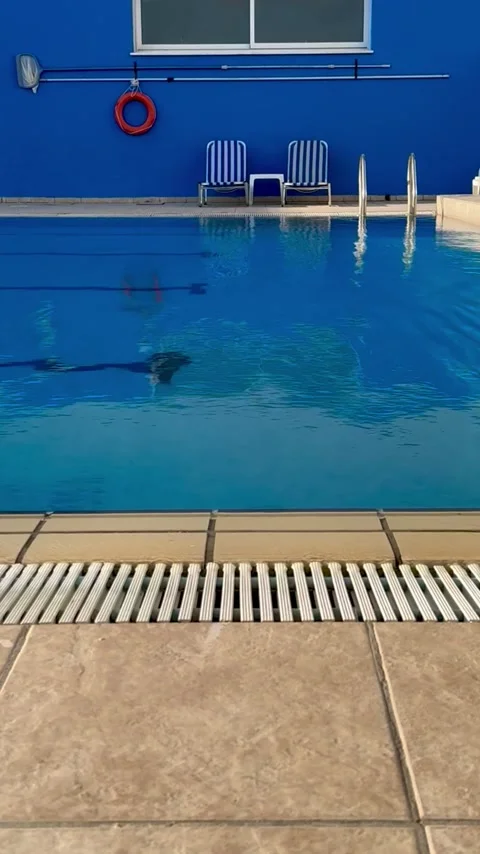 Static video of clear blue swimming pool with tiled deck Stock Footage 317542429