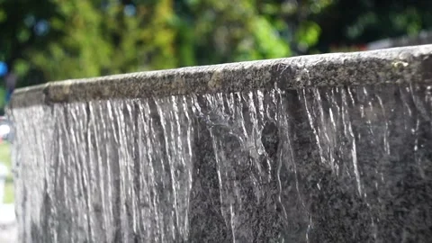 A static video of the falling waves of water in a fountain made of dark bro.. Stock Footage 276444788