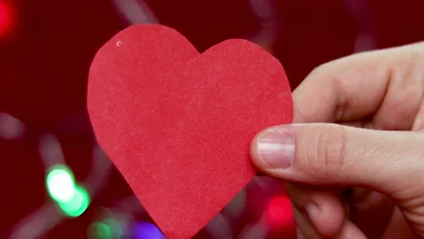 Static video of a red or orange (light brown) paper heart holded by a girl hand Video stock 167913444