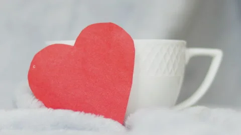 Static video of a red paper heart in front of a white ceramic tea Stock Footage 167432472