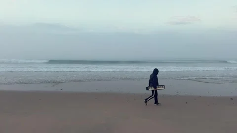 Static view of man in black with portable piano strolling on the beach. Stock Footage 276340230