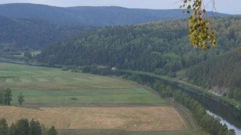 Static view from a mountain to a slow river, haystacks and pine forest 動画素材 83994760