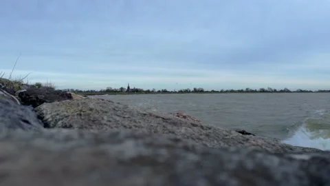 Static view over a lake with calm waves splashing on the boulders 動画素材 229498735