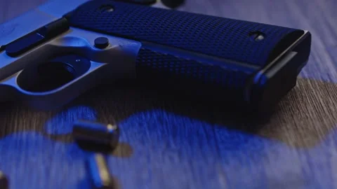 Static view of pistol grip and spent bullet casings on crime scene lit by Stock Footage 242977076