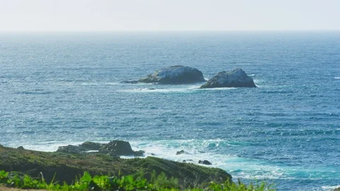 Static view of two large rock islands off Monterey CA coast on hazy afternoon Stock Footage 123564610