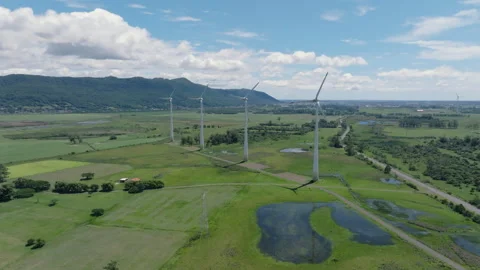 Static wide aerial view of four massive wind turbines and an electric Stock Footage 327350819