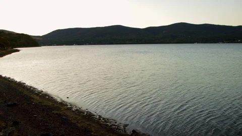 Static wide shot of calm lake water and rocky shoreline in Japan at dawn Stock Footage 321117092