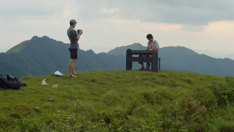 Static Wide Shot of Cameraman Filming Vintage Asian Musician on Mountain Peak Stock Footage 340400065