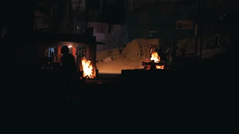 Static wide shot of cremation pyres burning on riverbank at night in Varanasi 库存影片 348800598