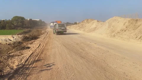 Static wide shot of a dusty, damaged rural road in India, vehicles moving Vídeos de archivo 327627630