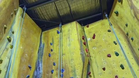 Static Wide Shot of Indoor Climbing Wall with Color-Coded Routes and Ropes 库存影片 313873360