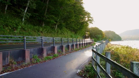 Static wide shot of lakeside road and pedestrian path in Japan Stock Footage 321120656