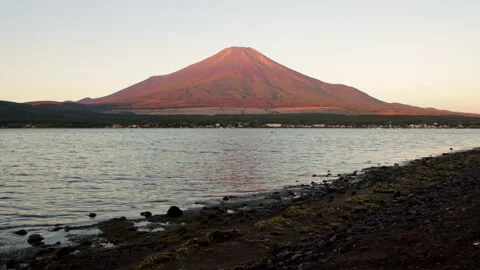 Static wide shot of Mount Fuji with rocky shoreline at Lake Yamanaka at dawn Stock Footage 321117604