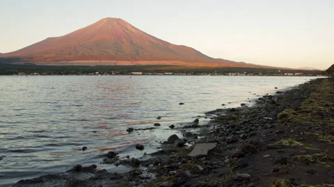 Static wide shot of Mount Fuji and Lake Yamanaka with rocky shoreline at dawn Stock Footage 321118463