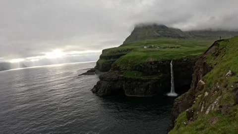 Static wide shot of Mulafossur waterfall and Gasadalur village with sea birds Stock Footage 337558571