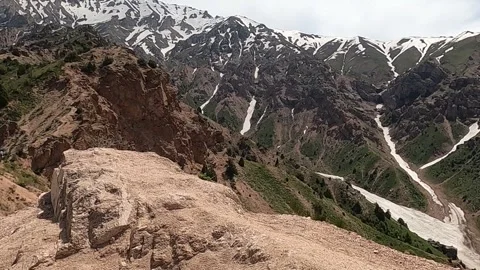 Static wide shot of rocky cliffs and snow-capped peaks in Chimgan mountains Stock Footage 335475810