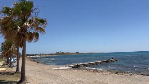 Static wide shot of a tropical sandy beach with a stone pier in the sea Stock Footage 336320438
