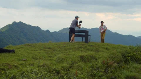 Static Wide Shot of Videographer Adjusting Camera on Mountain Peak BTS Stock Footage 340396329