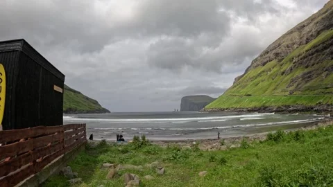 Static wide shot of volcanic black sand beach with dark cabin in foreground Stock Footage 339628170