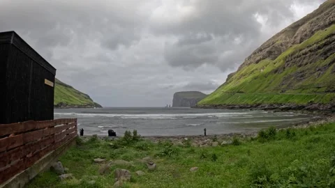 Static wide shot of volcanic black sand beach with dark cabin in foreground Stock Footage 339713090