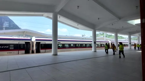 Station staff walking along a platform next to a modern train at Luang Prabang Stock Footage 325365842