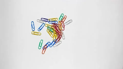 Stationery colored paper clips move on a white surface. Stock Footage 151699571