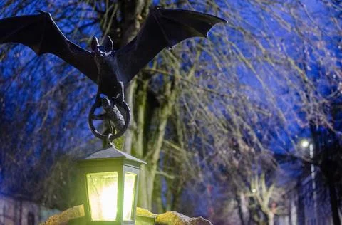 The statue of a bat with a flashlight in its paws at night. Stock Photos