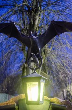 The statue of a bat with a flashlight in its paws at night. Stock Photos