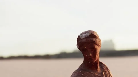 Statue on the beach during sunset with city buildings in the background Stock Footage 342049182