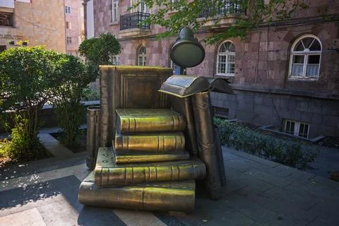 A statue of a book is sitting on top of a stack of books 스톡 사진