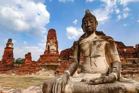 A statue of a Buddha is sitting in front of a large building Stock Photos