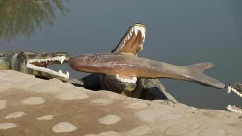 A statue of a crocodile catching a fish Stock Photos