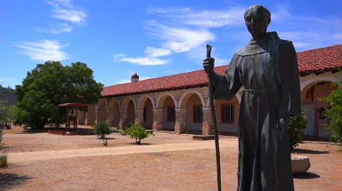 A statue of Father Junipero Serra stands in front of a California Mission. Video stock 47110028