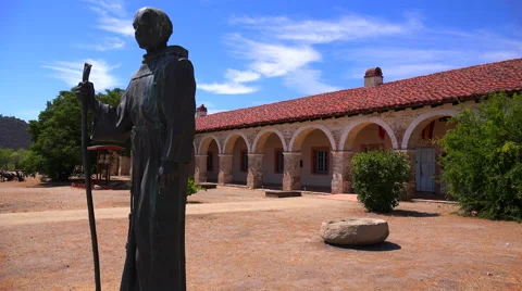 A statue of Father Junipero Serra stands in front of a California Mission. Stock Footage 47110343