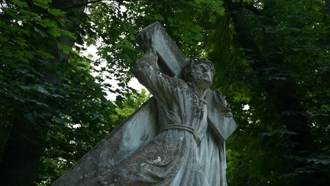 Statue of jesus carrying a cross on a background of trees 스톡 동영상 115033045