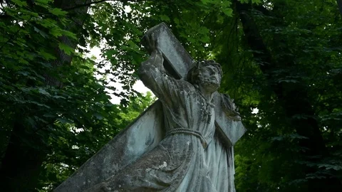 Statue of jesus carrying a cross on a background of trees 스톡 동영상 115033424