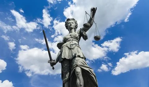 Statue of Justitia (justice goddess) on cloudy blue sky Stock Photos