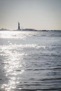 Statue of Liberty shape against light from lower tip of Manhattan Stock Photos